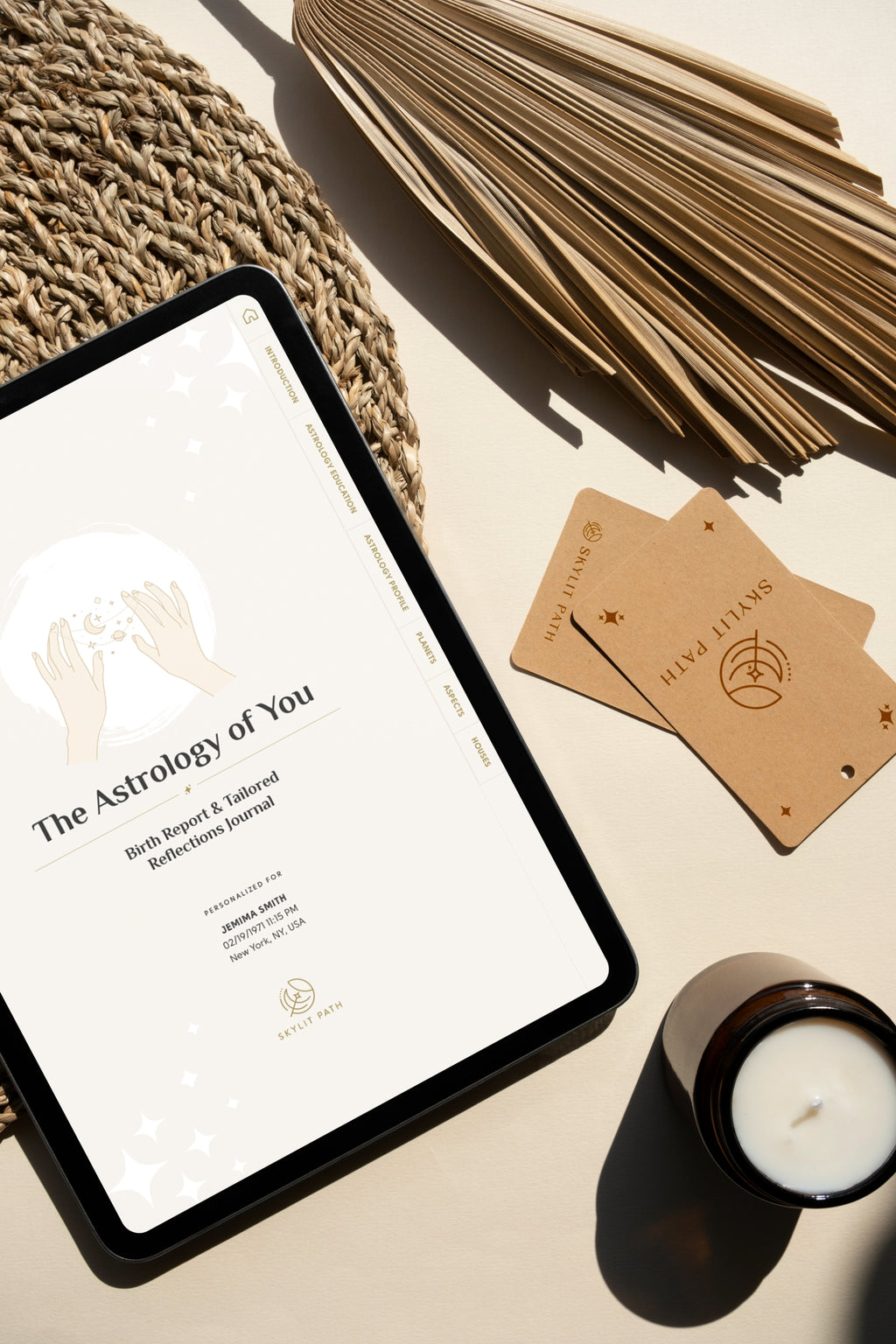 Tablet displaying 'The Astrology of You' journal on a table with cards and a candle.